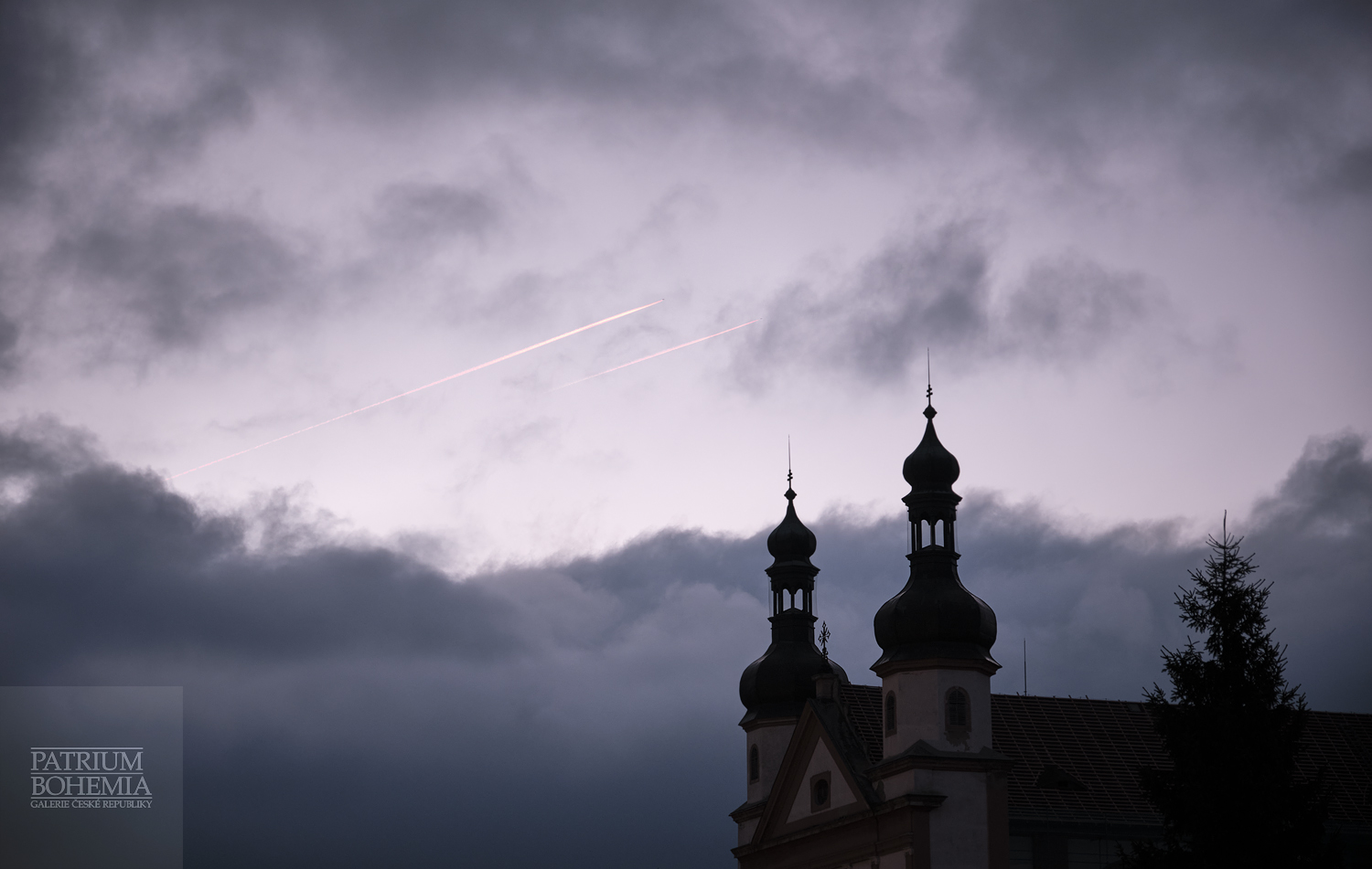 Dvě ranní letecké linky nad věžemi kostela sv. Ignáce. Chomutov.