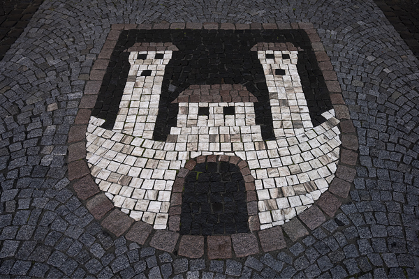Znak města Žatec vytvořený v dlážděném chodníku před vchodem radnice.